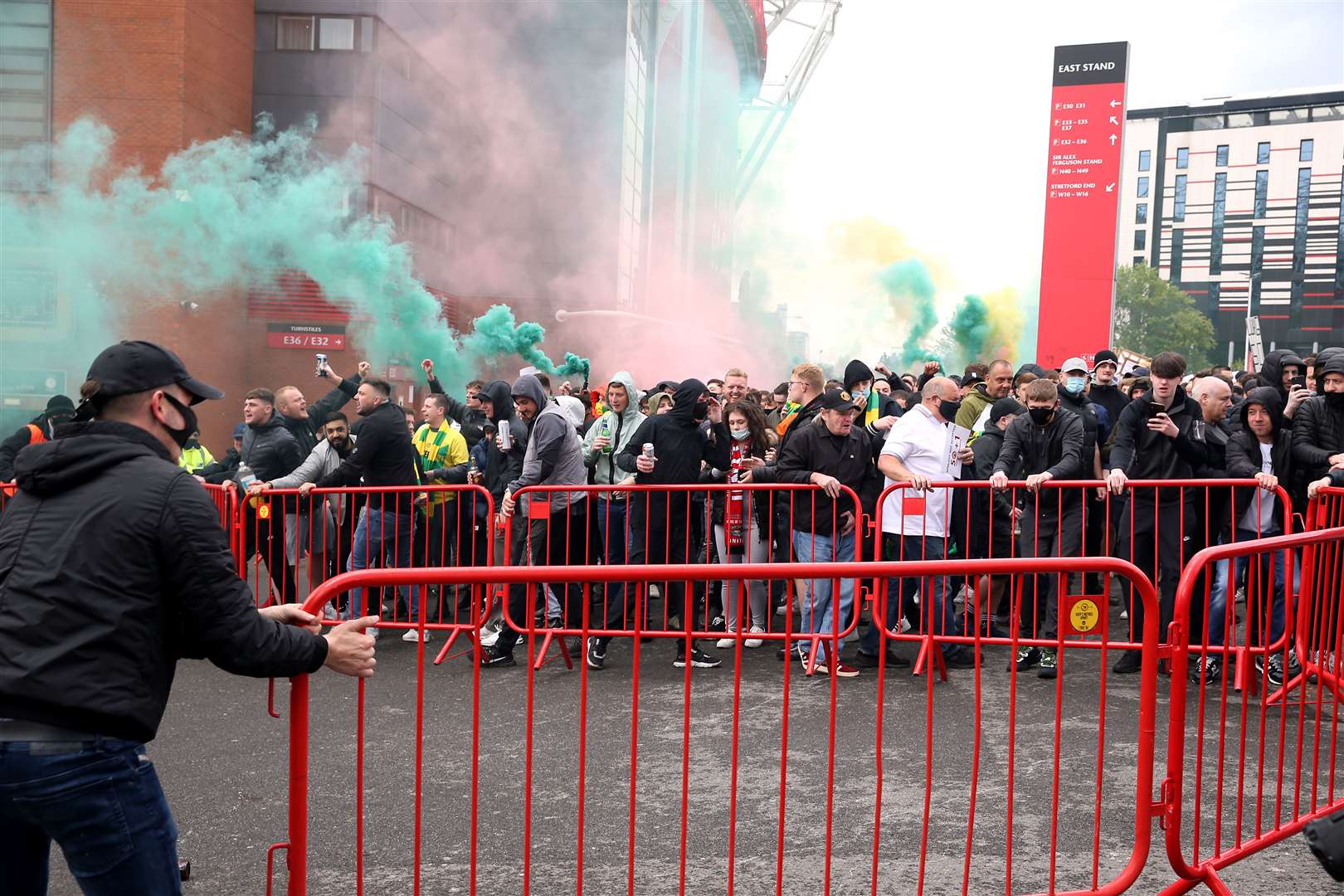 Fans move barriers outside the ground as they let off flares whilst protesting against the Glazer family (Barrington Coombs/PA)