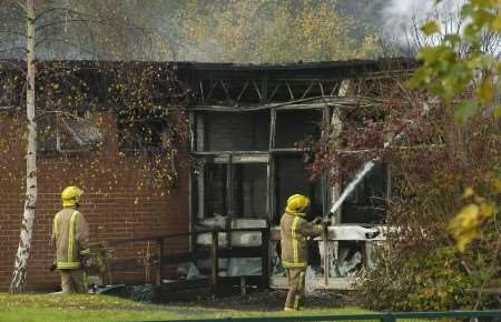 Firefighters deal with the smouldering remains of the blaze. Picture: NICK JOHNSON