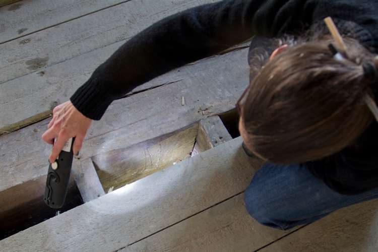 National Trust archaeologist Nathalie Cohen inspecting the witchmarks. Picture: National Trust, Martin Havens