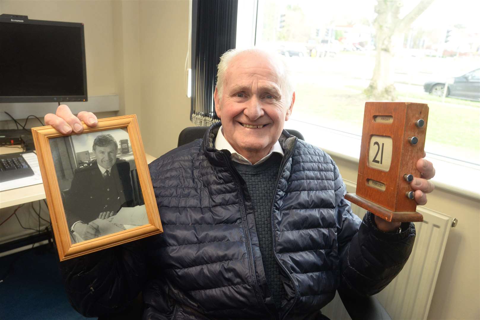 Doug, in his old office, holding a calender which features in the photo he is holding of himself from his time as the station commander. Picture: Chris Davey