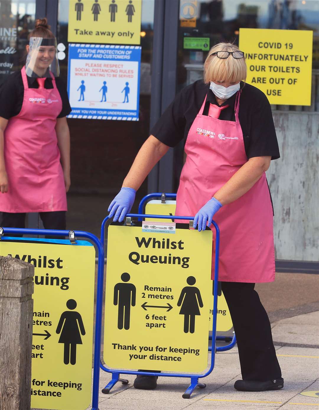 Staff at the Coastline fish and chip shop and ice cream parlour on Blyth beach, Northumberland, put out social distancing signs for customers (Owen Humphreys/PA)