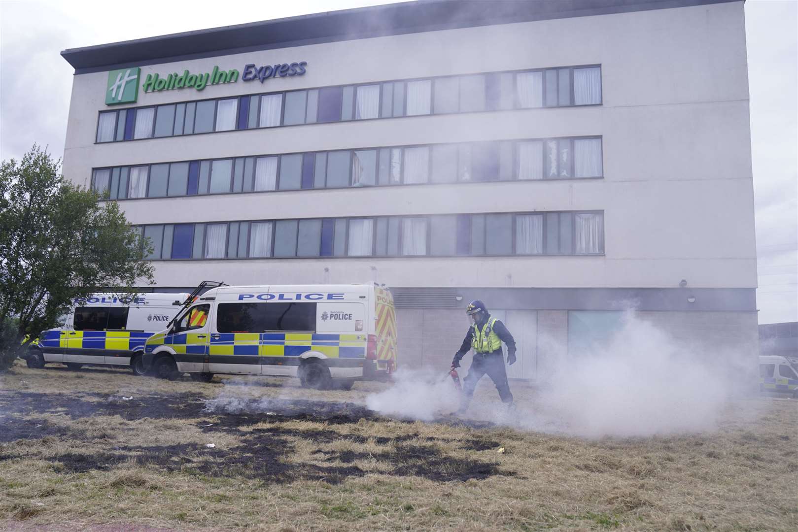 A police officer extinguishes a fire during an anti-immigration demonstration outside the Holiday Inn Express in Rotherham (Danny Lawson/PA)