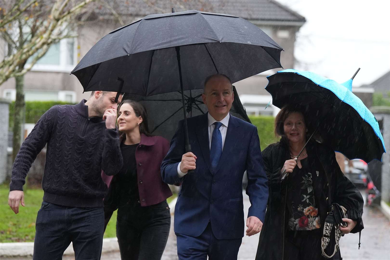 Tanaiste and Fianna Fail leader Micheal Martin arrives with an umbrella to cast his vote, accompanied by his family (Jacob King/PA)