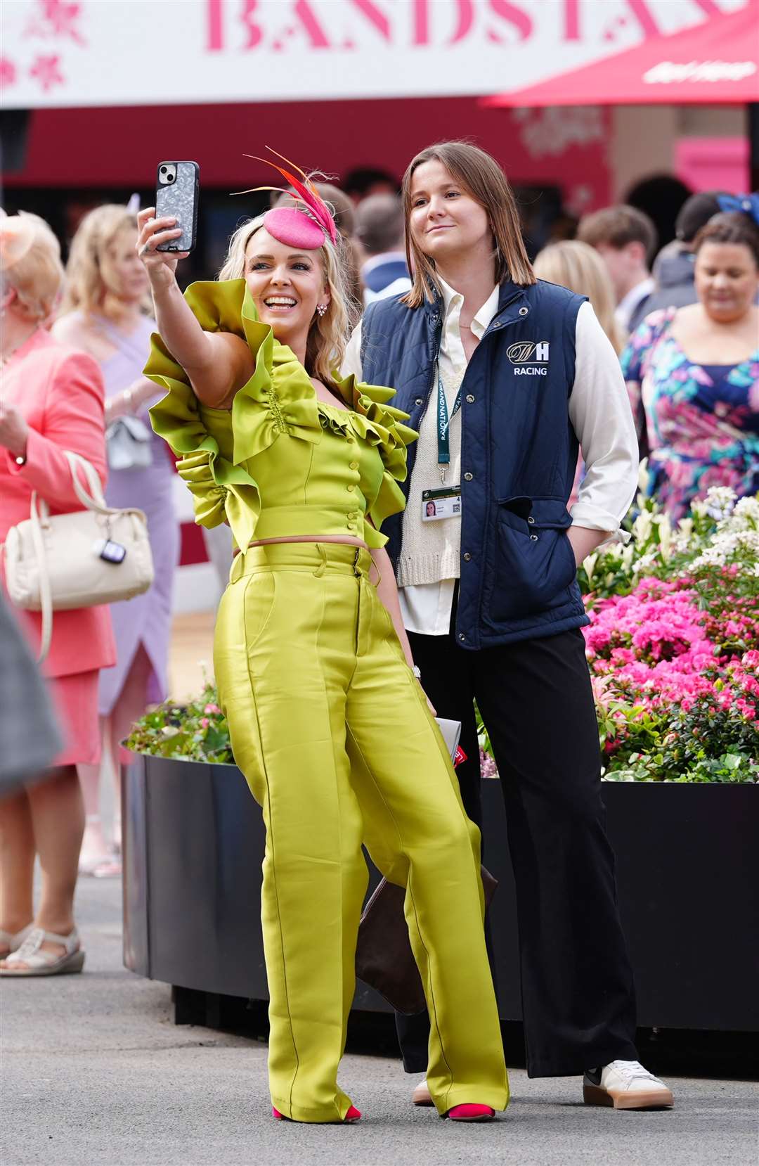 A racegoer dressed in brightly coloured trouser suit takes a selfie (Peter Byrne/PA)