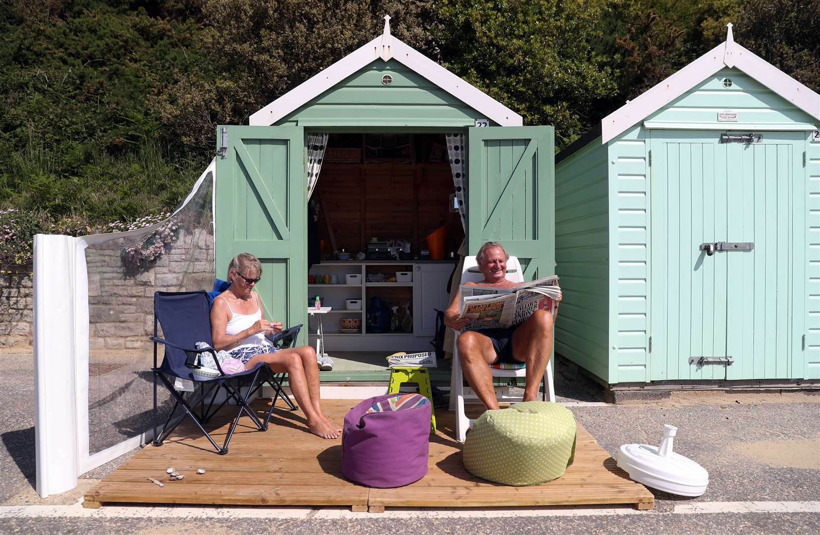 Rob and Sally Underhill sit outside their beach hut as they enjoy the hot weather in Dorset (Andrew Matthews/PA)