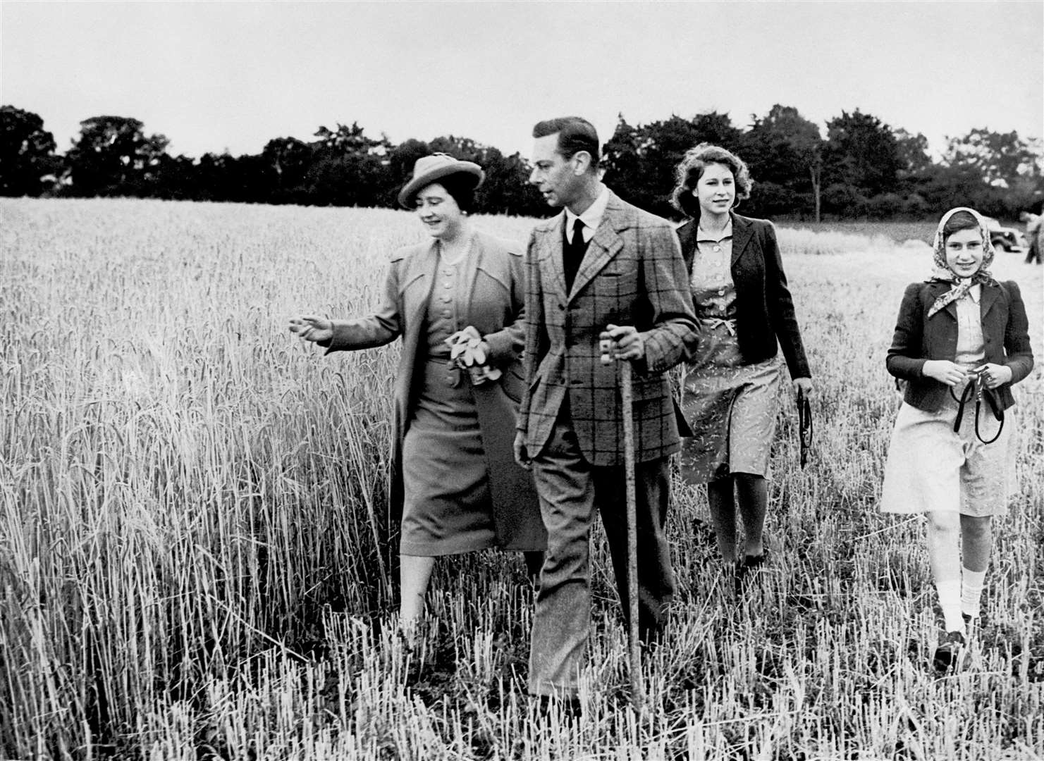 King George VI and Queen Elizabeth walk in a field with their daughters Princess Elizabeth and Princess Margaret in 1941 during the war (PA)