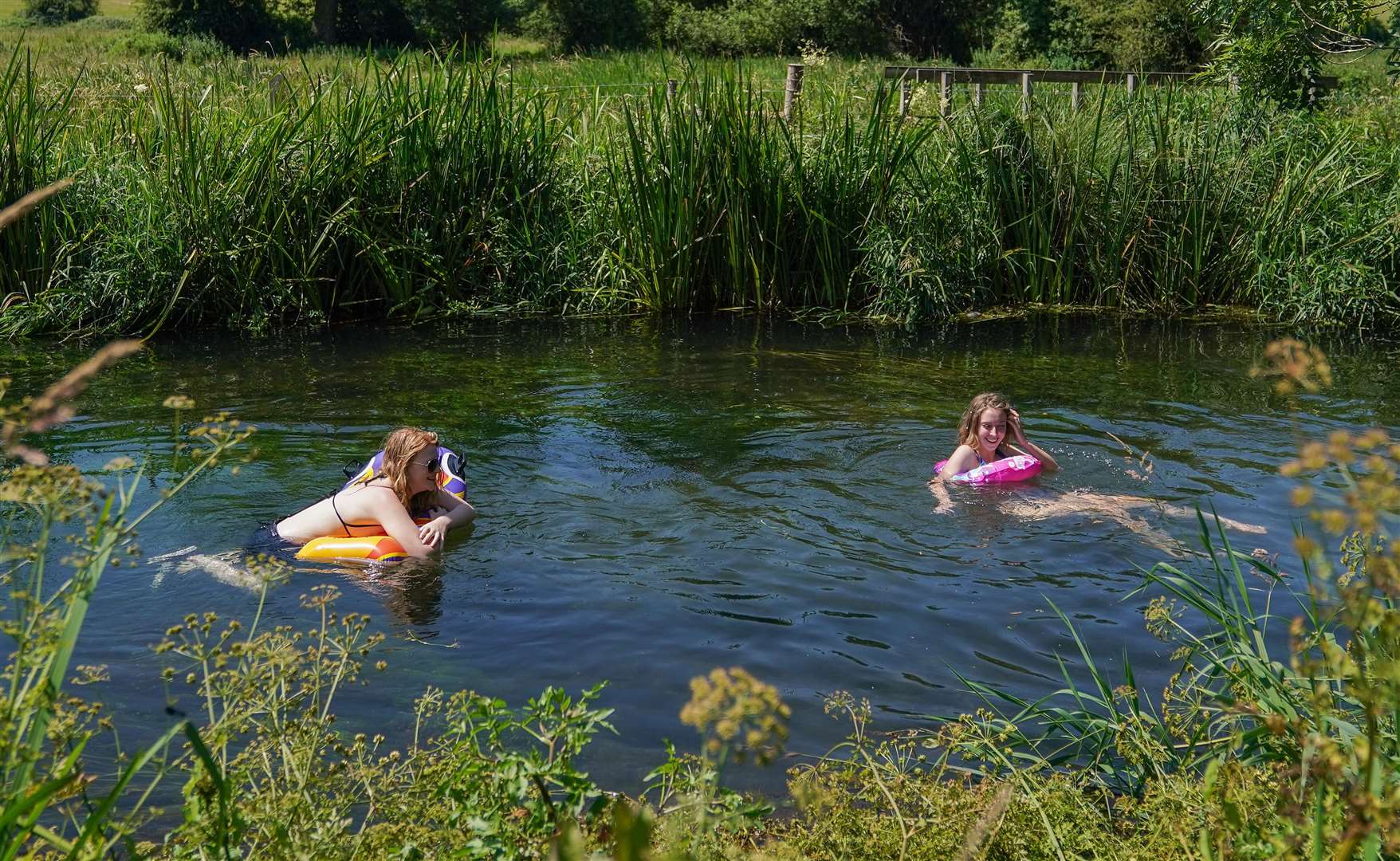 Two people use inflatables to make their way along the river Itchen near to Twyford in Hampshire (Andrew Matthews/PA)