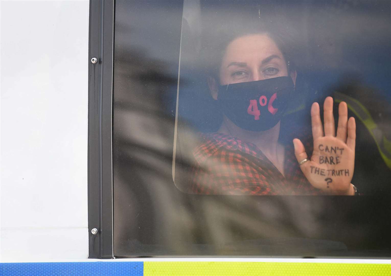 An Extinction Rebellion protester in a police van outside the Houses of Parliament (Victoria Jones/PA)