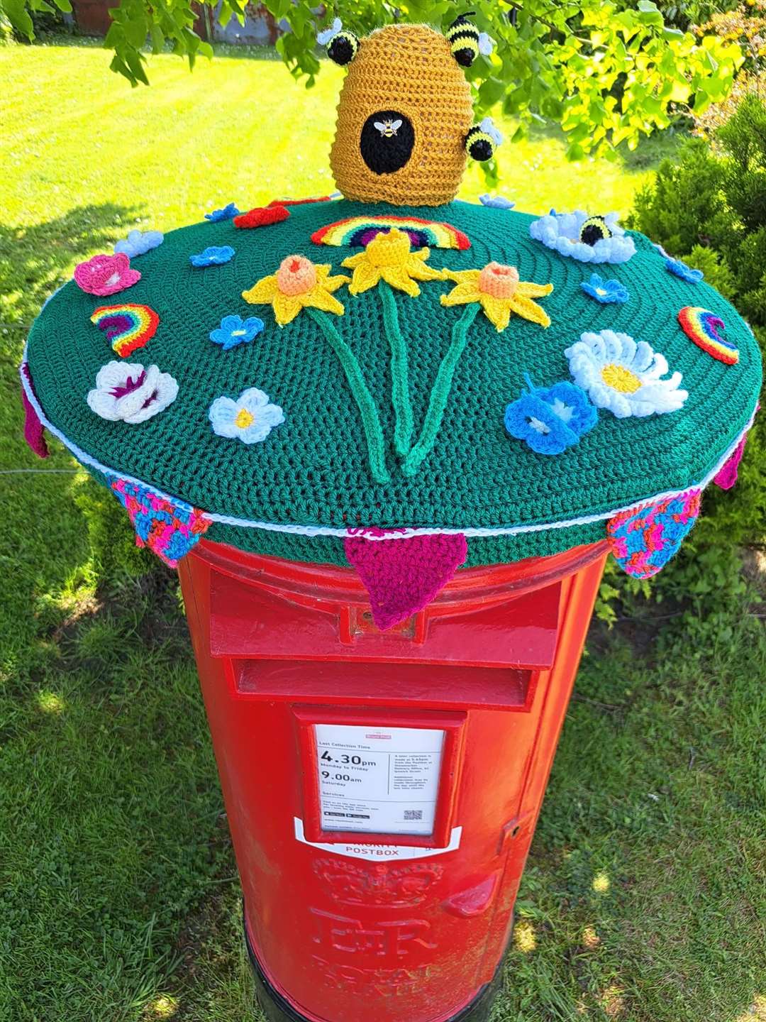 Bev Mayhew’s spring postbox topper which features crocheted flowers and a beehive (Bev Mayhew/PA)