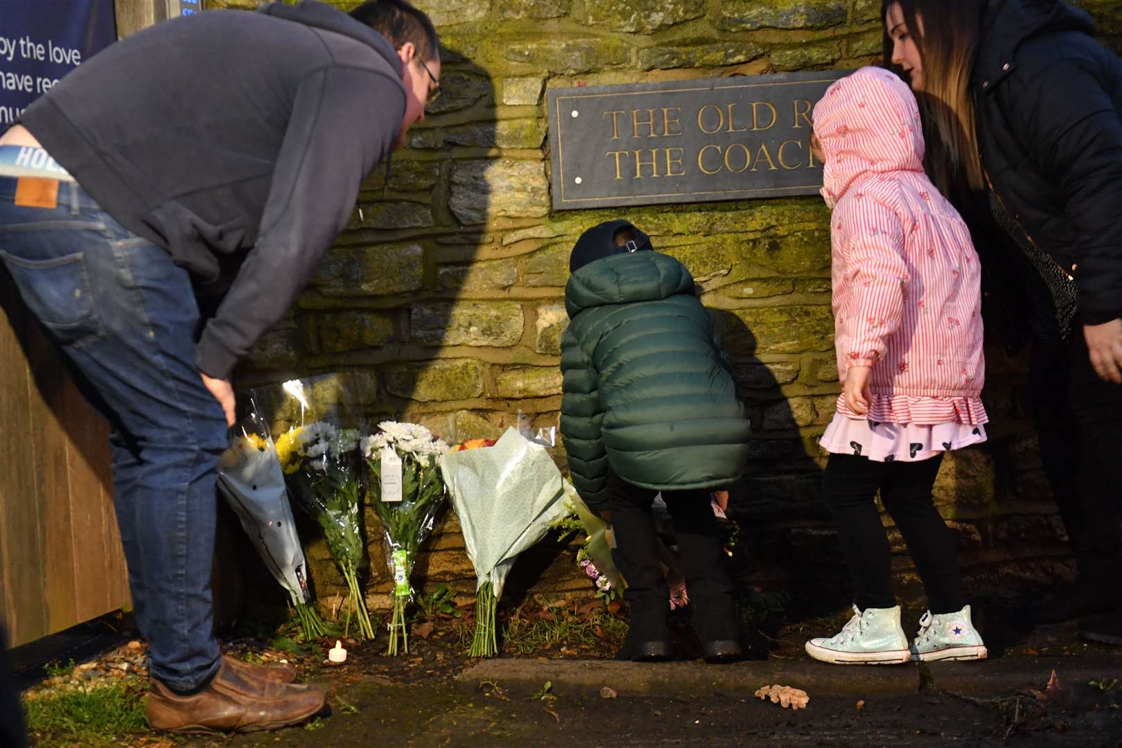 A family leaves a floral tribute outside the home in Marston Moretaine, (Jacob King/PA)