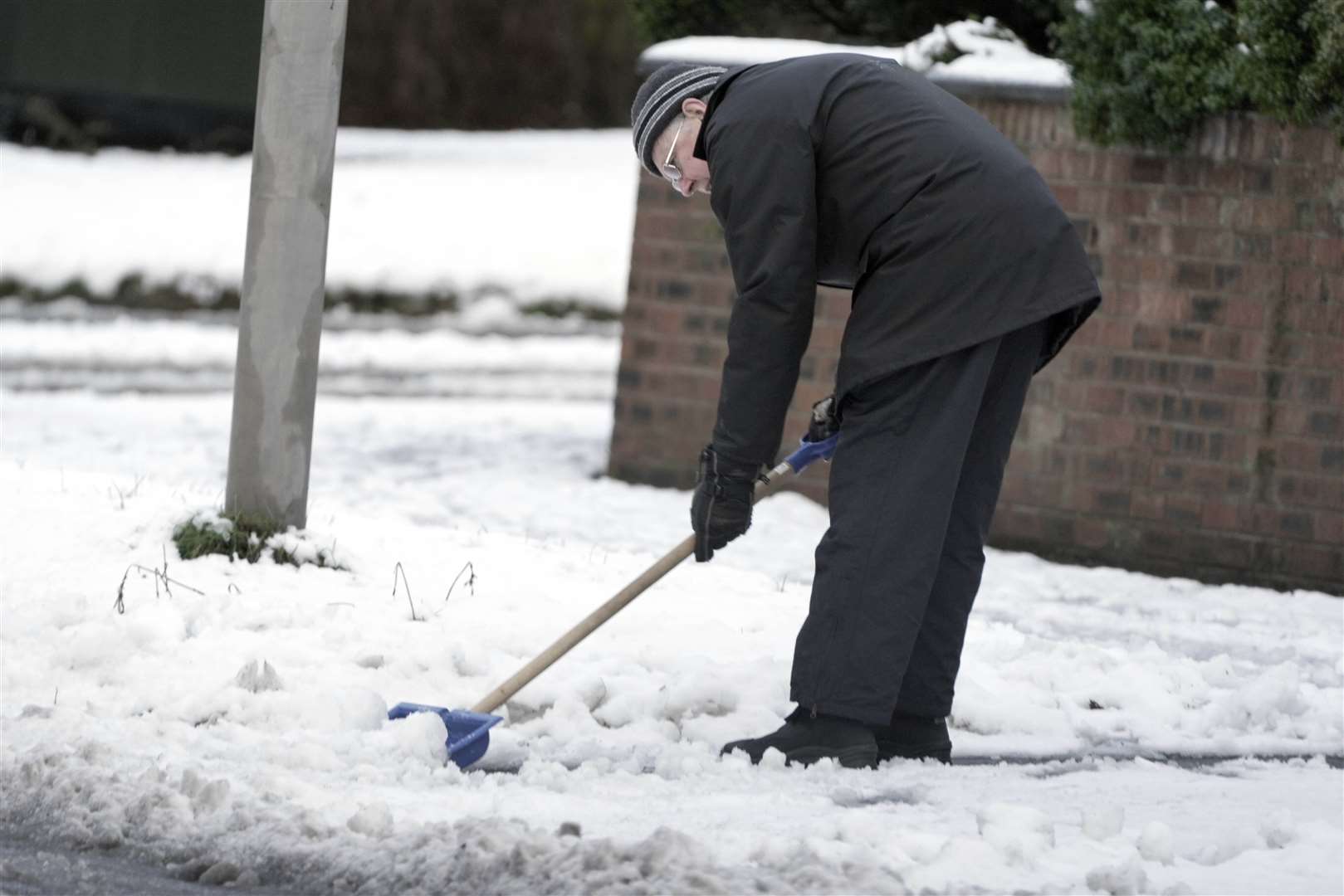 A man clears snow from the pavement in Woolton, Liverpool (Peter Byrne/PA)