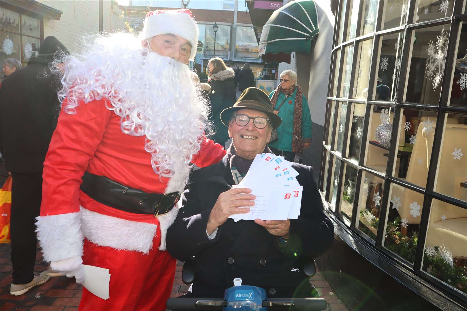 Sittingbourne's 'whistling postman' Dale Howting, pictured with some of cheques he will be posting, along with Santa Mike Day from the Methodist church, has collected £12,800 for charity this year
