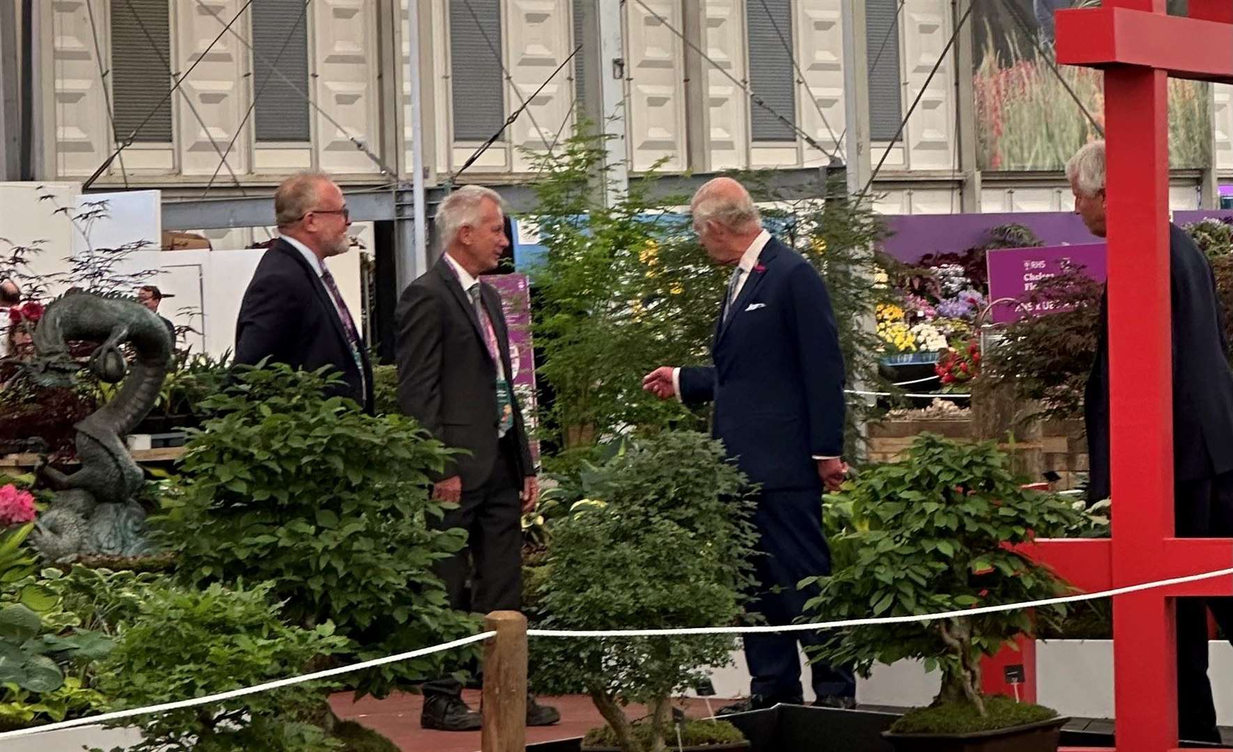 King Charles discusses Yamadori bonsai trees with Paul Harris of Brookfield Plants, Ashford and, left, Matthew Ball of Clearwater Koi, Ashford, who helped build the stand. Picture: Marc Stevenson