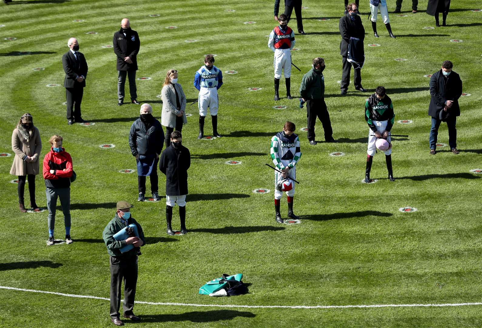 Jockeys and owners in the parade ring observe a silence in honour of the Duke of Edinburgh who has died aged 99 during Ladies Day of the 2021 Randox Health Grand National Festival at Aintree Racecourse, Liverpool (David Davies/Jockey Club/PA)