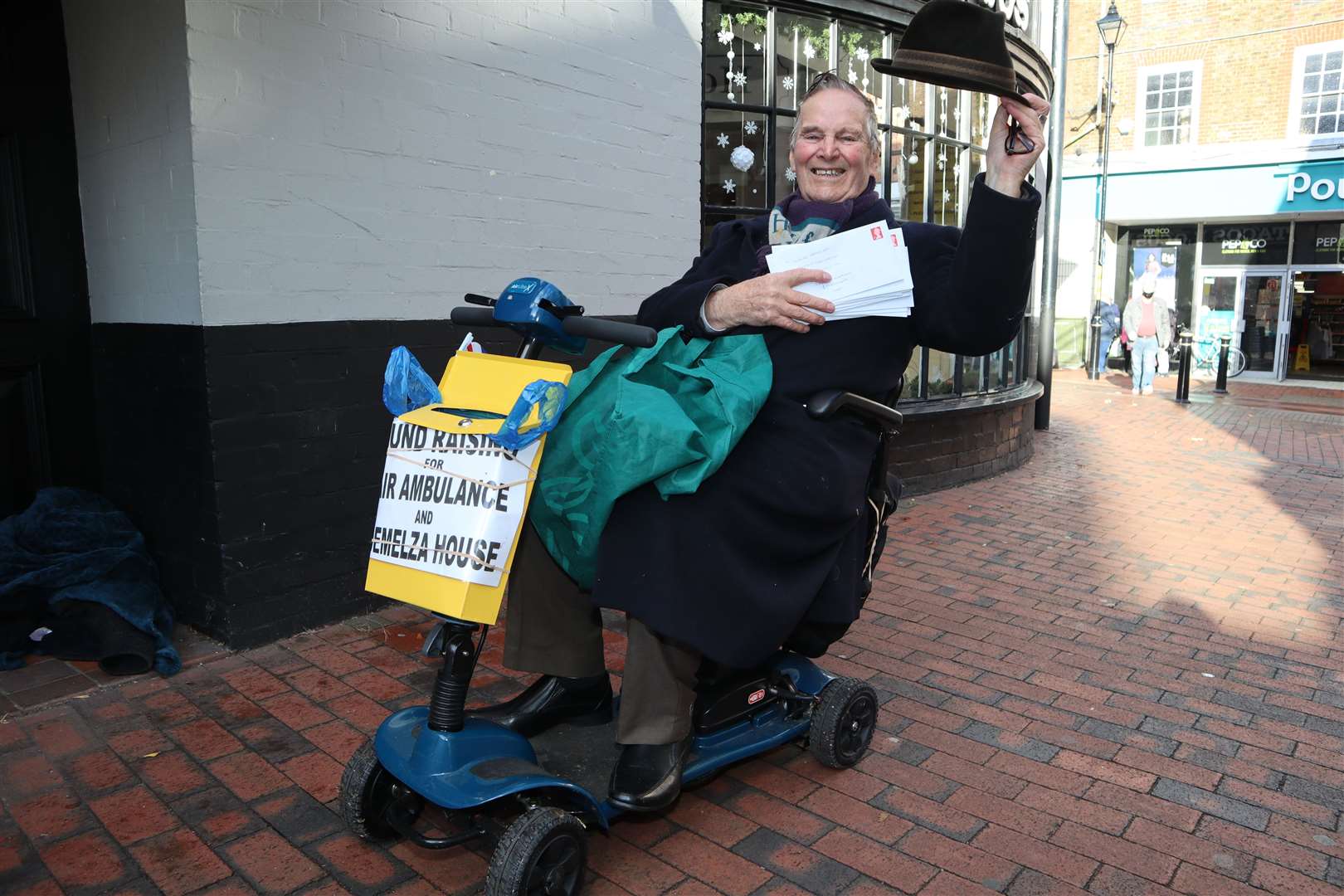 Sittingbourne's 'whistling postman' Dale Howting, pictured with some of cheques he will be posting along with his new electric mobility scooter, has collected £12,800 for charity this year