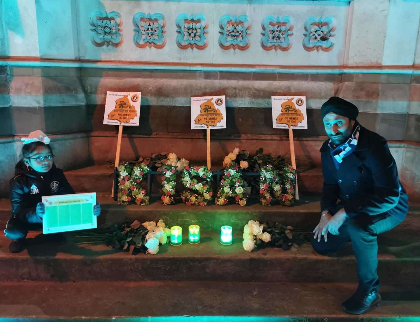 Satinder Hayre, right and his son Jeevan Hayre, left lay placards and candles.