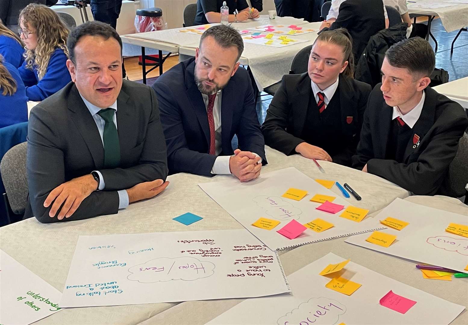 SDLP leader Colum Eastwood and former taoiseach Leo Varadkar talking to schoolchildren at the event in Derry’s Playhouse (David Young/PA).