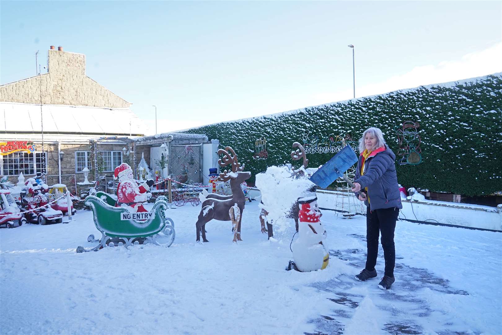 Elaine Armstrong clears snow from her garden in Burnopfield, County Durham (Owen Humphreys/PA)