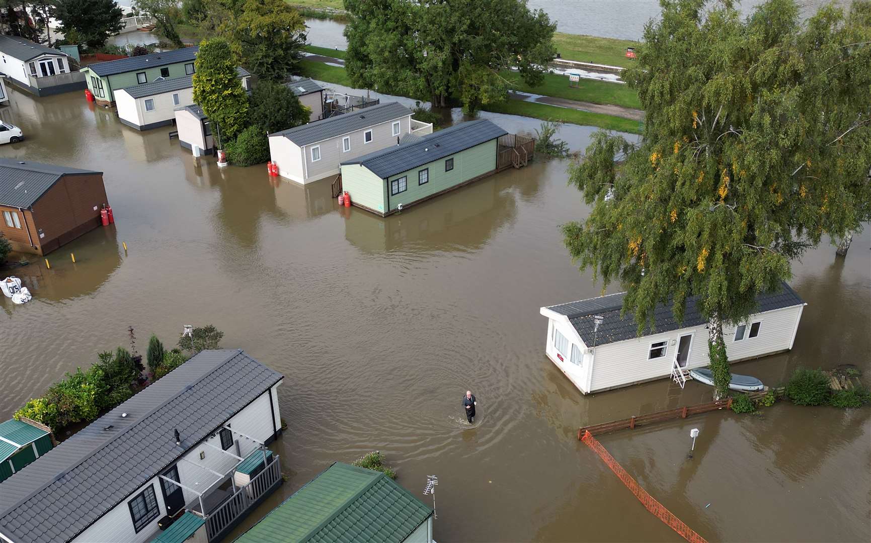 A man wades through floodwater at Cogenhoe Mill holiday park in Northamptonshire, which is next to Billing Aquadrome holiday park (Joe Giddens/PA)