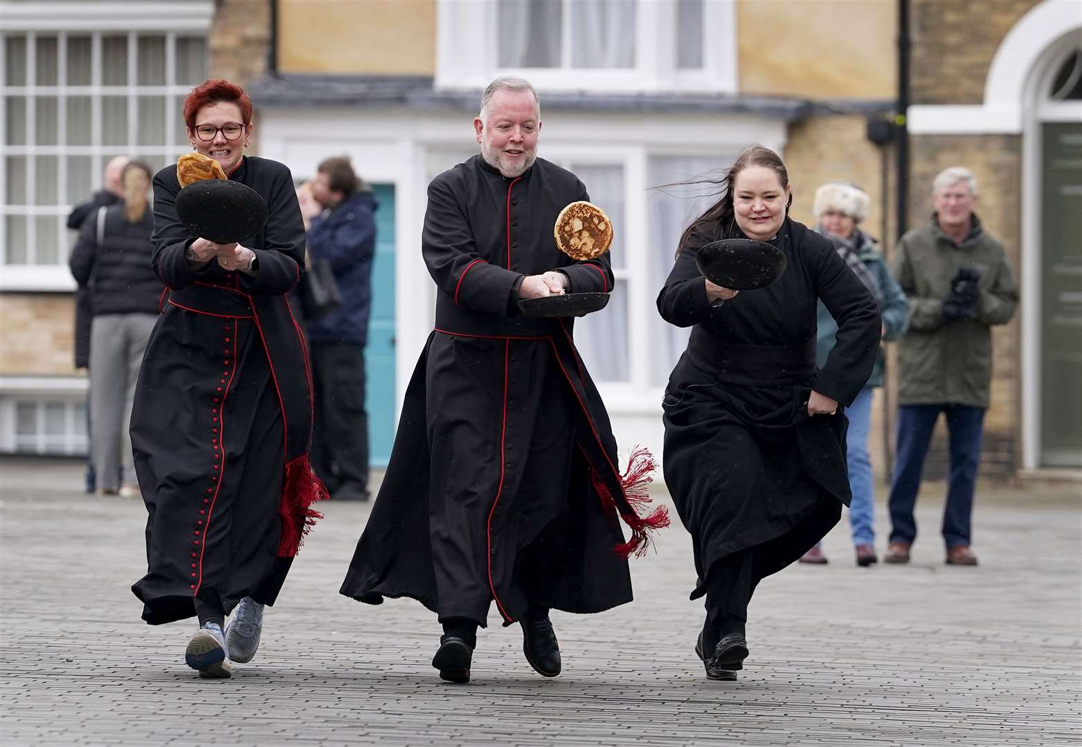 The Very Reverend Dr David Monteith, Dean of Canterbury Cathedral (centre) takes part in a Shrove Tuesday pancake race with members of the clergy at Canterbury Cathedral in Kent (Gareth Fuller/PA)