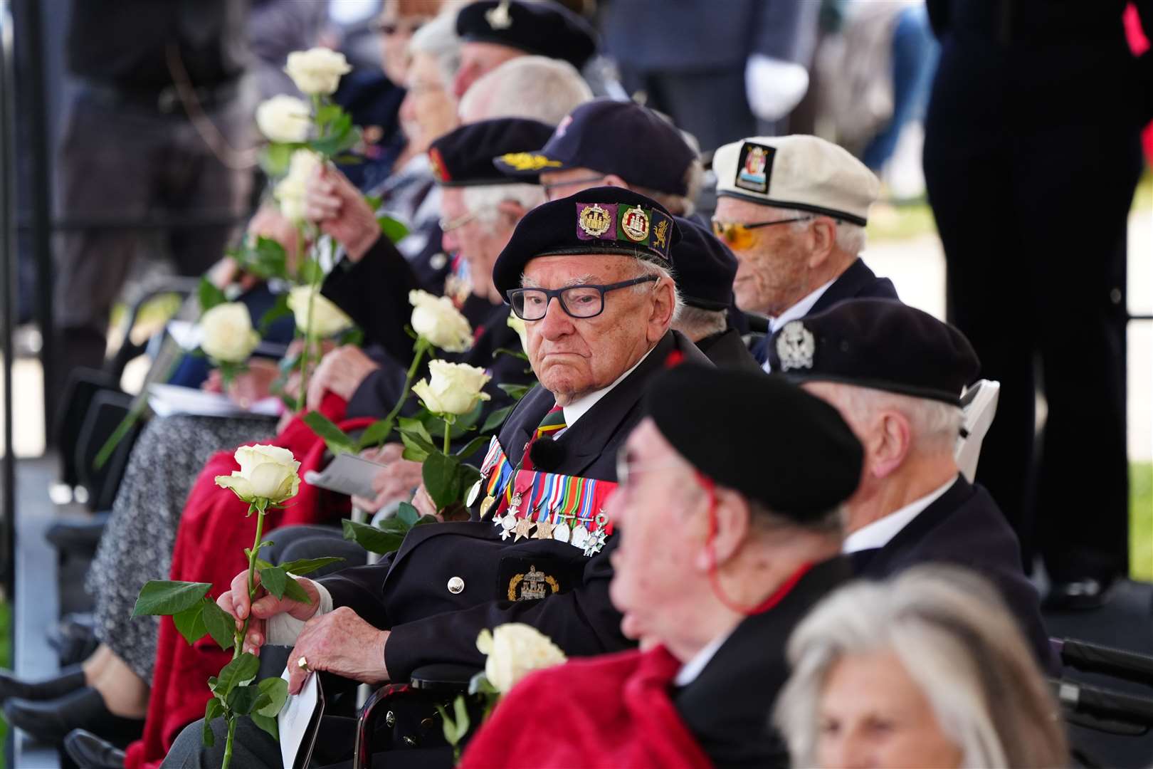 Veterans holding roses which they received from schoolchildren during the event in Normandy (Jane Barlow/PA)