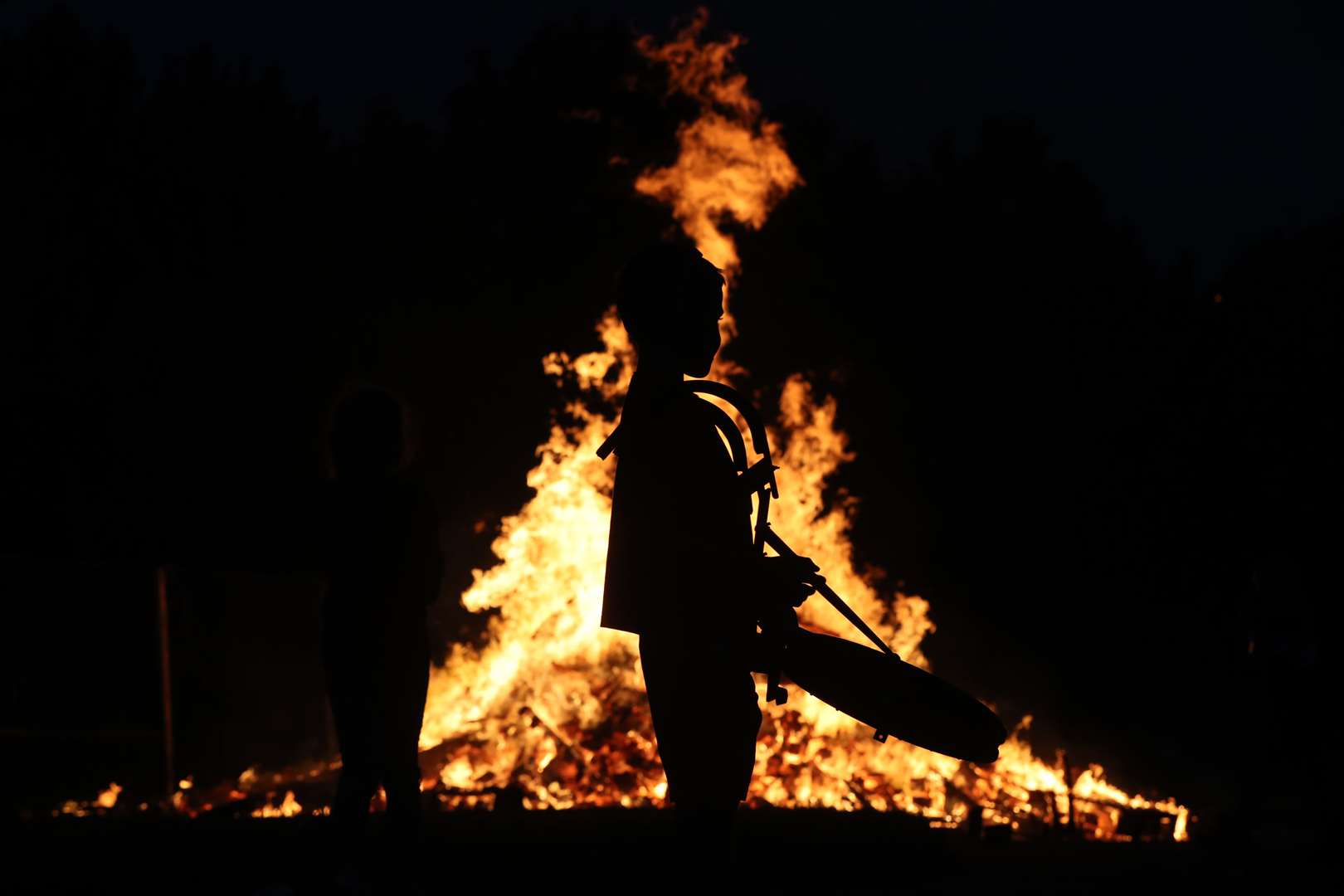 A young boy plays drums by a bonfire on Belfast’s Shankill Road as bonfires were lit at midnight (Niall Carson/PA)