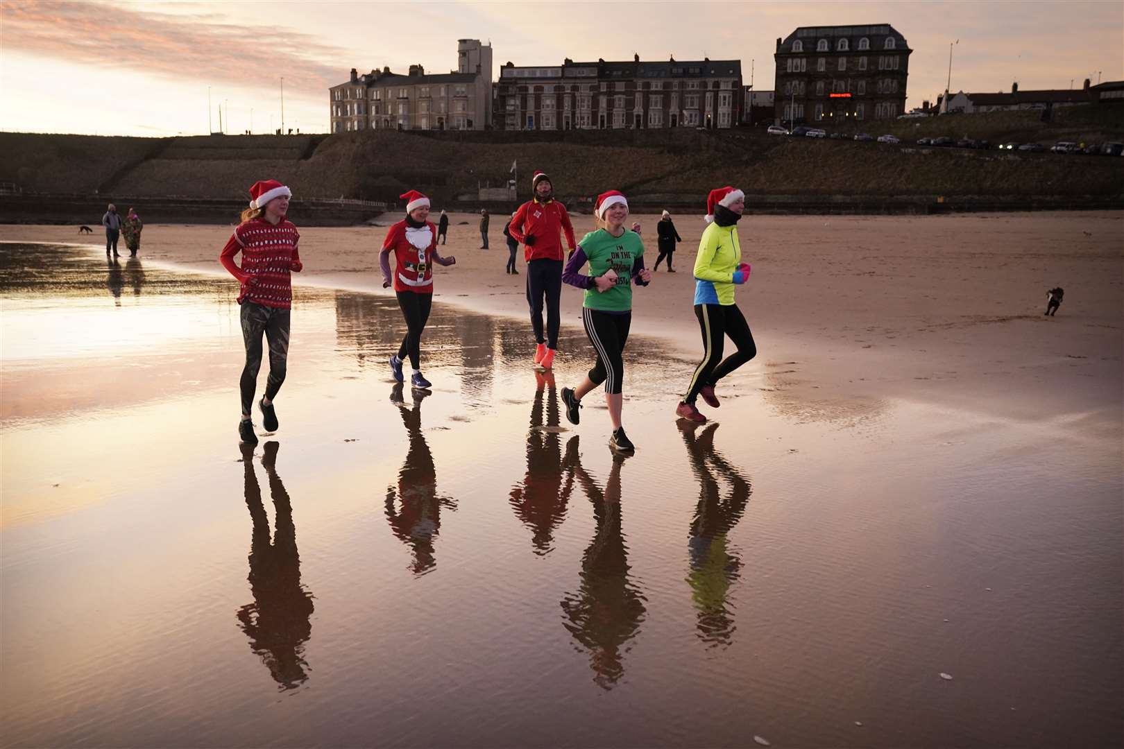 Joggers take an early morning Christmas Day run along Tynemouth Beach on the North East coast (Owen Humphreys/PA)