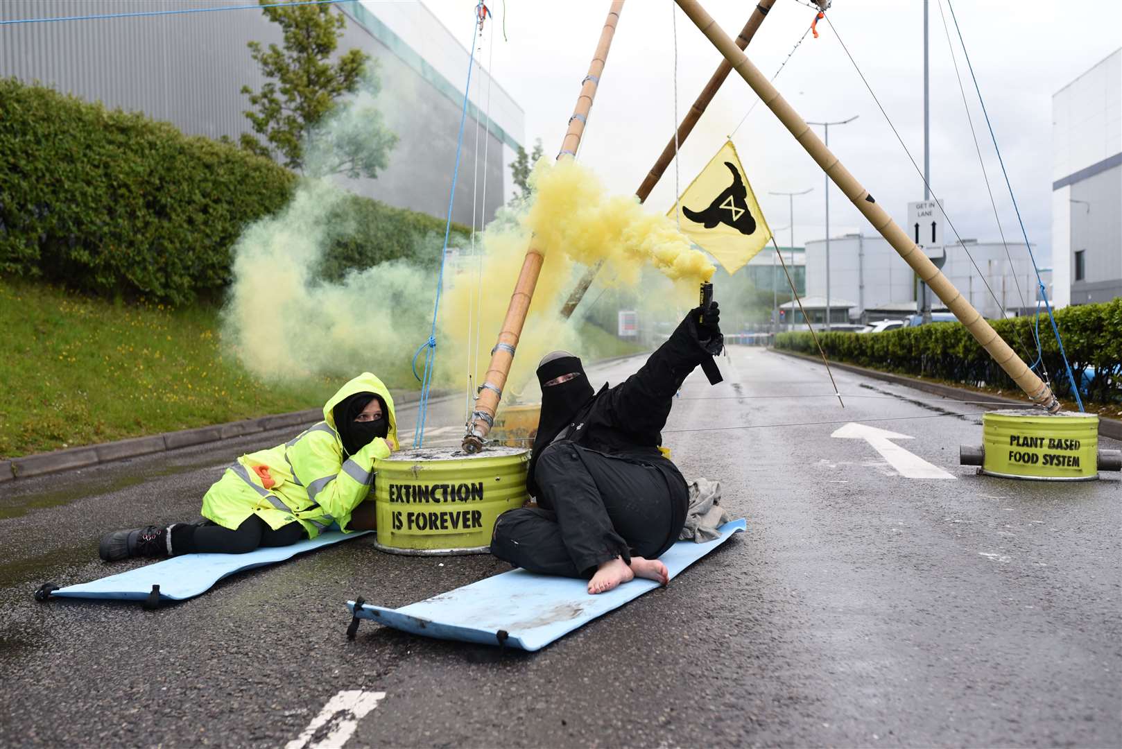 Protesters attached to a bamboo structure and releasing a yellow smoke canister in Basingstoke (Andrea Domeniconi/Animal Rebellion/PA)