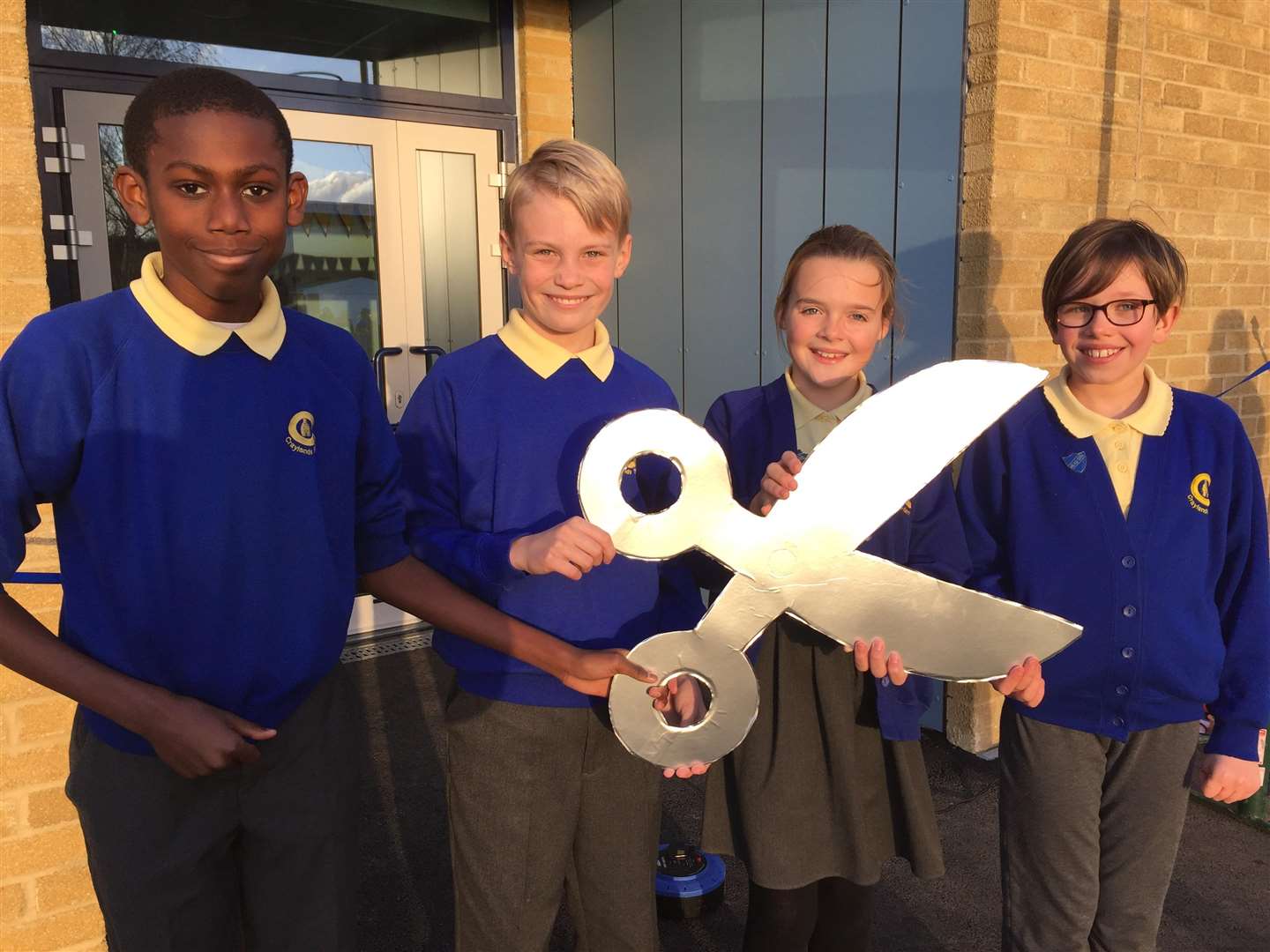 The children passed shiny replica pair of scissors from one end of the line to the other at the ceremony