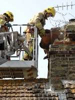 Firefighters survey a damaged chimney. Picture: PAUL DENNIS