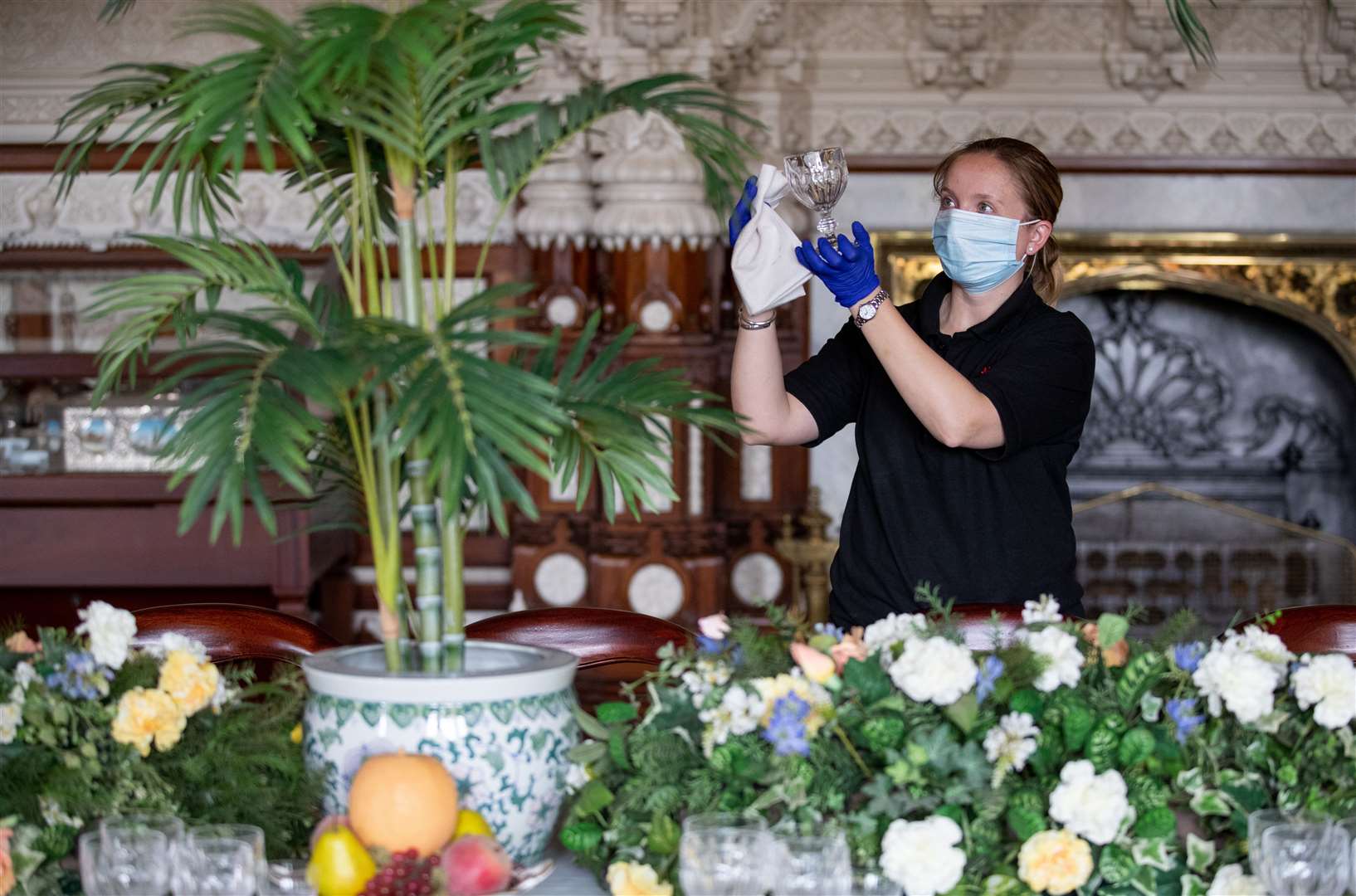 An English Heritage conservator cleans a glass from the dining table inside the Durbar room at Osborne on the Isle of Wight (Andrew Matthews/PA)