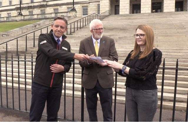 Travel agent Damien Murphy hands a letter to Caoimhe Archibald, chairwoman of Stormont’s Economy Committee (Rebecca Black/PA)