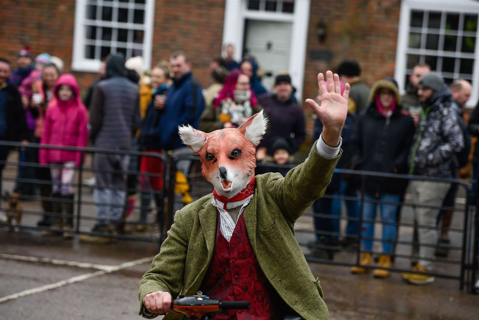 A person on a mobility scooter with a fox mask warming up the crowd before the hunt begins
