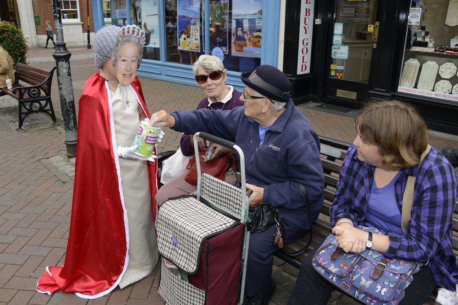 Bemused shoppers in Ashford donate to the Queen, aka John Kellam, collecting for Macmillan Cancer Research