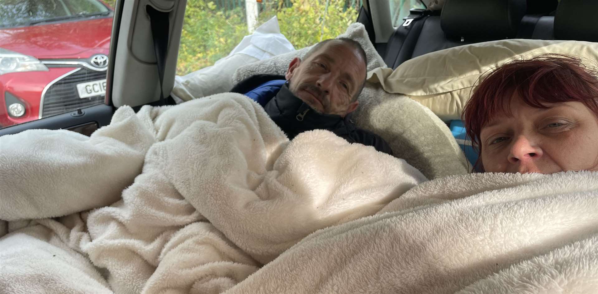 The couple's sleeping surrounded by pillows and blankets in the front seats