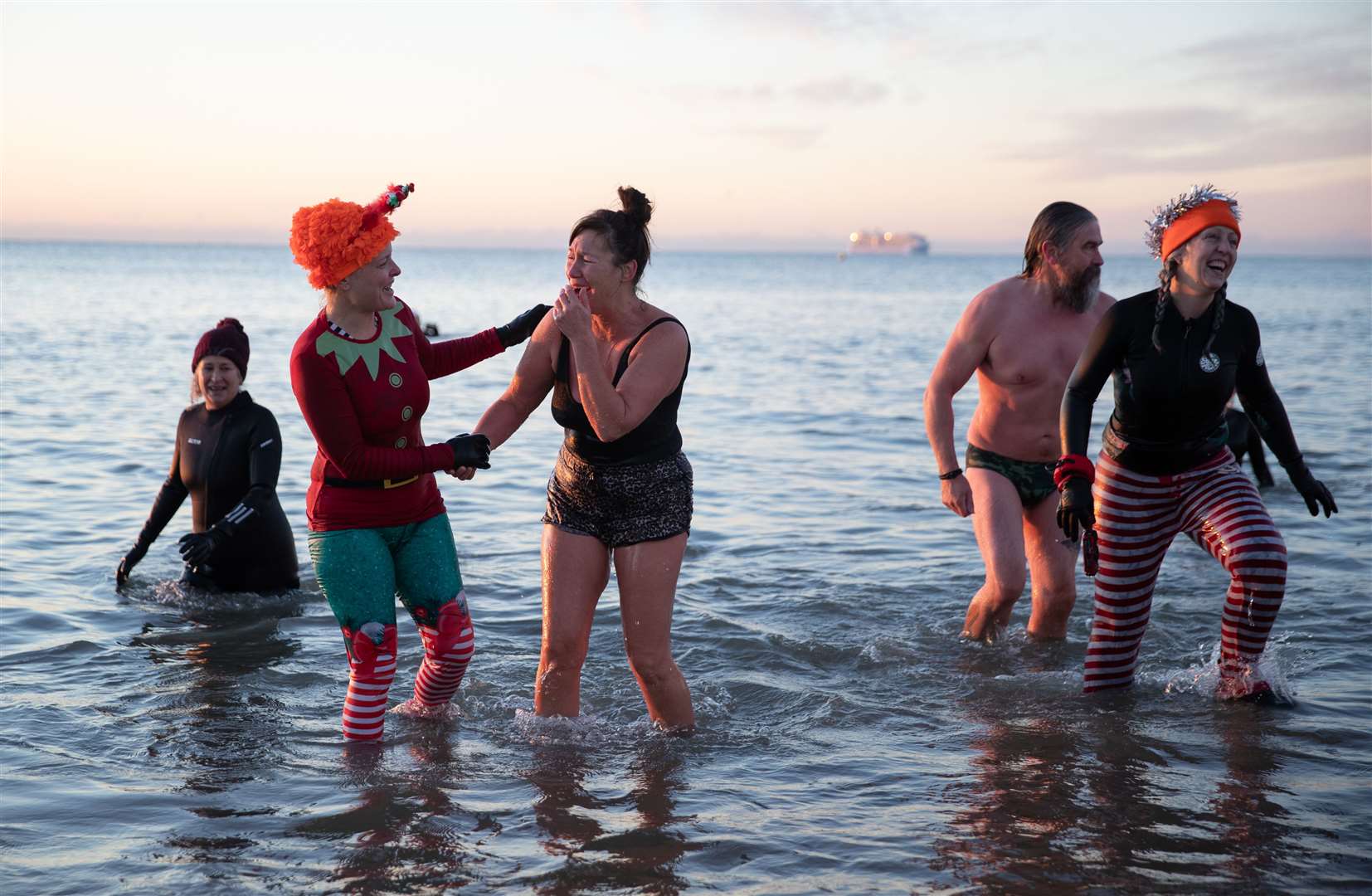 Swimmers make their way out of the sea at Boscombe beach in Dorset after going for a swim at sunrise (Andrew Matthews/PA)