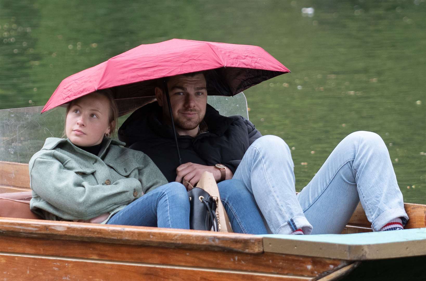 People shelter under umbrellas whilst punting along the River Cam in Cambridge (Joe Giddens/PA)