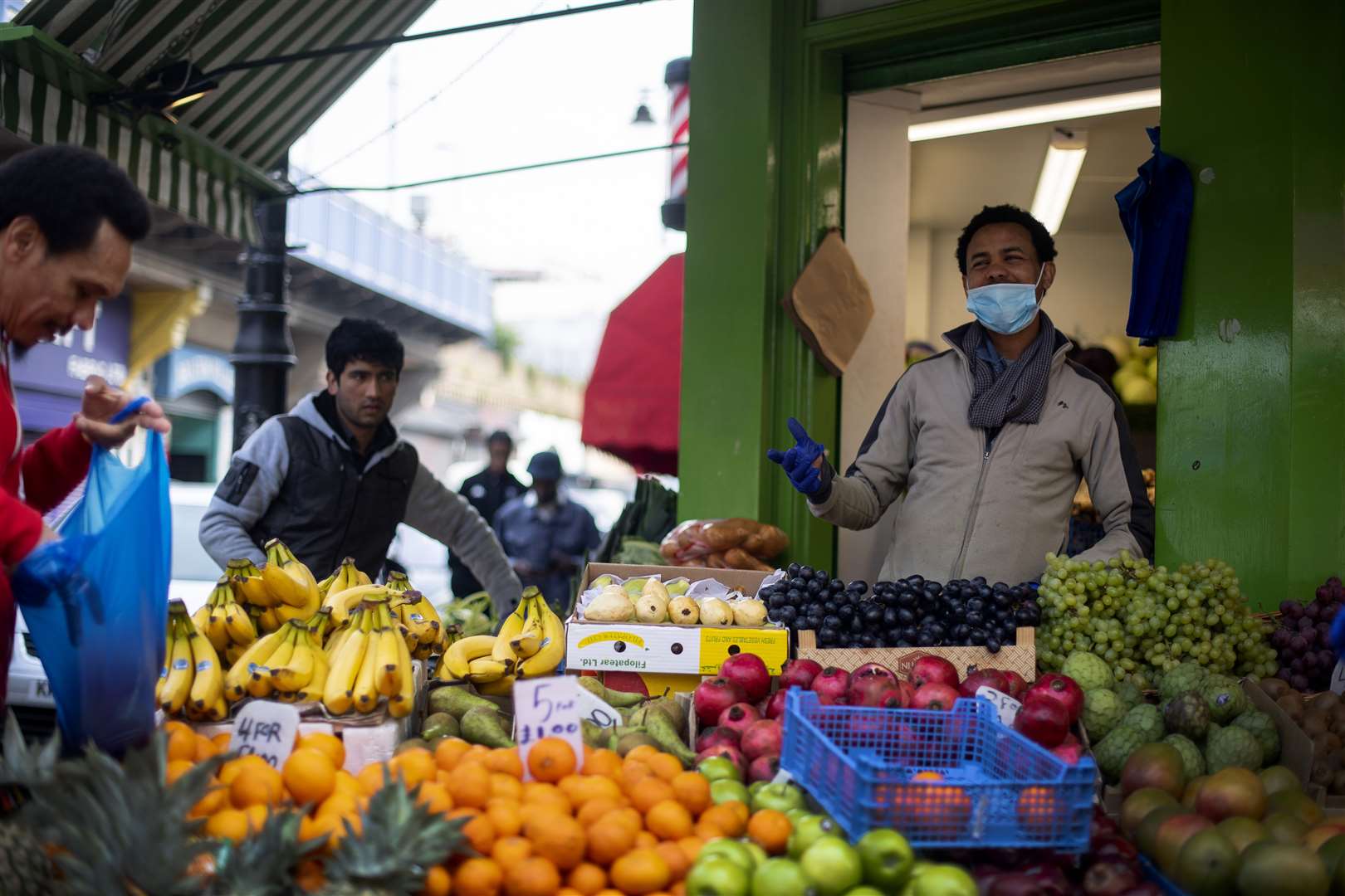 A stall holder in a protective face mask in Brixton Market in south London (Victoria Jones/PA)