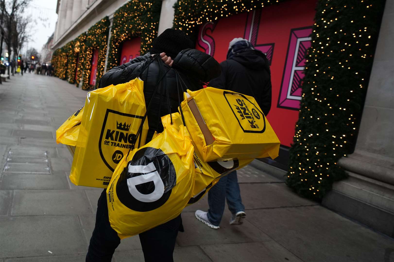 A man carries bags from JD Sports after shopping in the sales in London’s Oxford Street (Jordan Pettitt/PA)