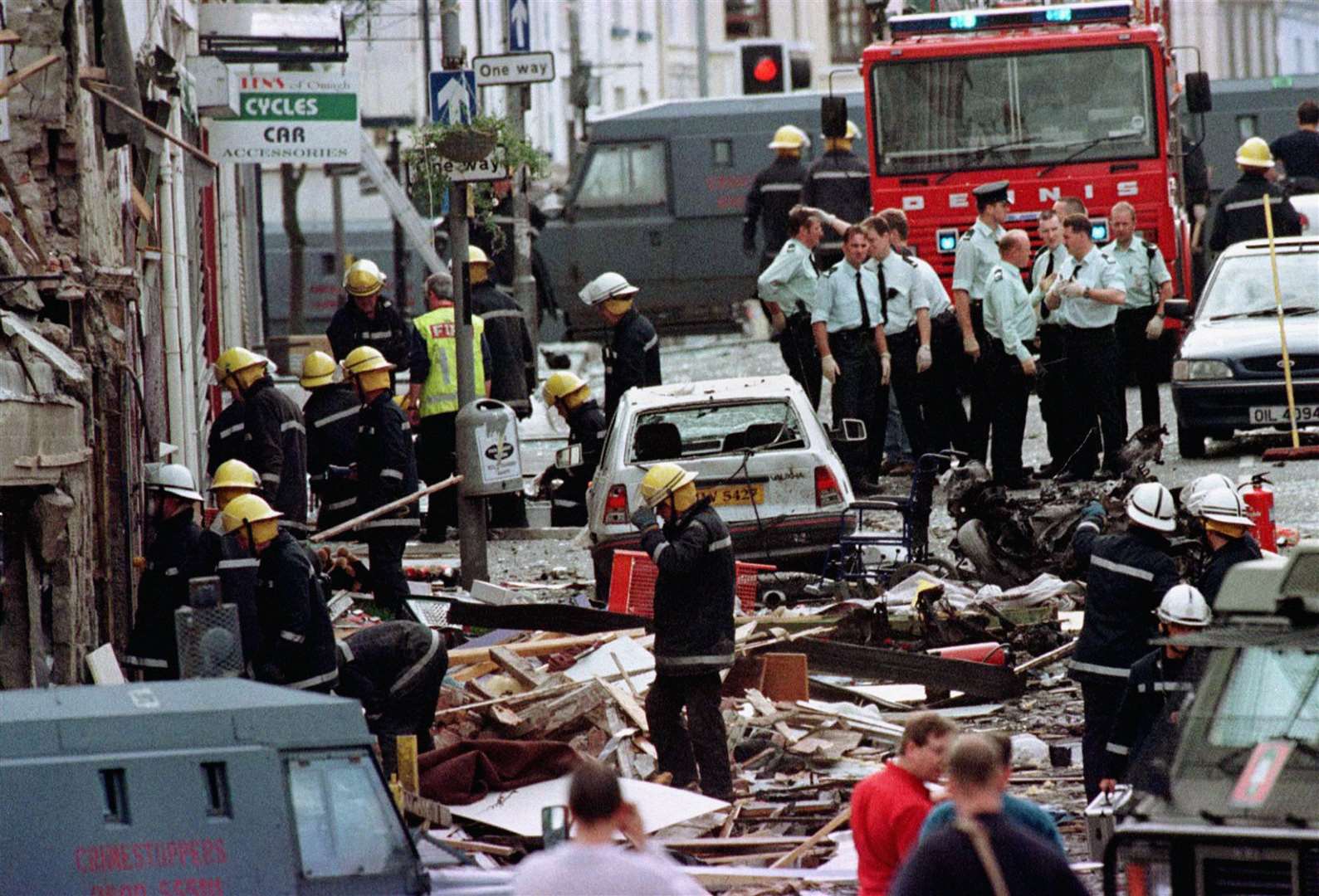 Police officers and firefighters inspecting the damage caused by a bomb explosion in Market Street, Omagh, in 1998 (Paul McErlane/PA)