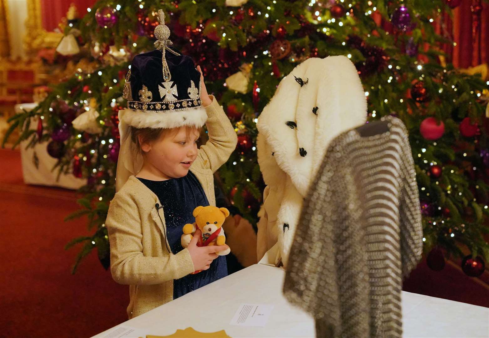Seven-year-old Olivia Taylor, with her teddy bear Corrie, wearing a replica of the Queen Mary crown (Jonathan Brady/PA)