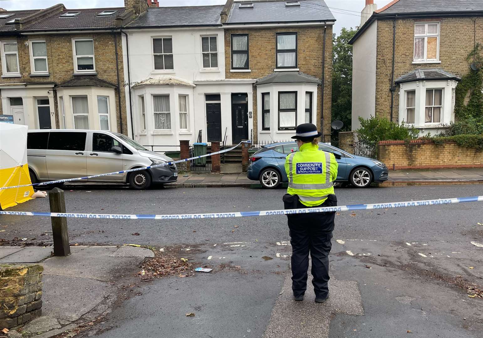 A Metropolitan police officer stands near a police cordon and forensic tent on Paget Terrace, near the scene in Eglinton Road (Rosie Shead/PA)