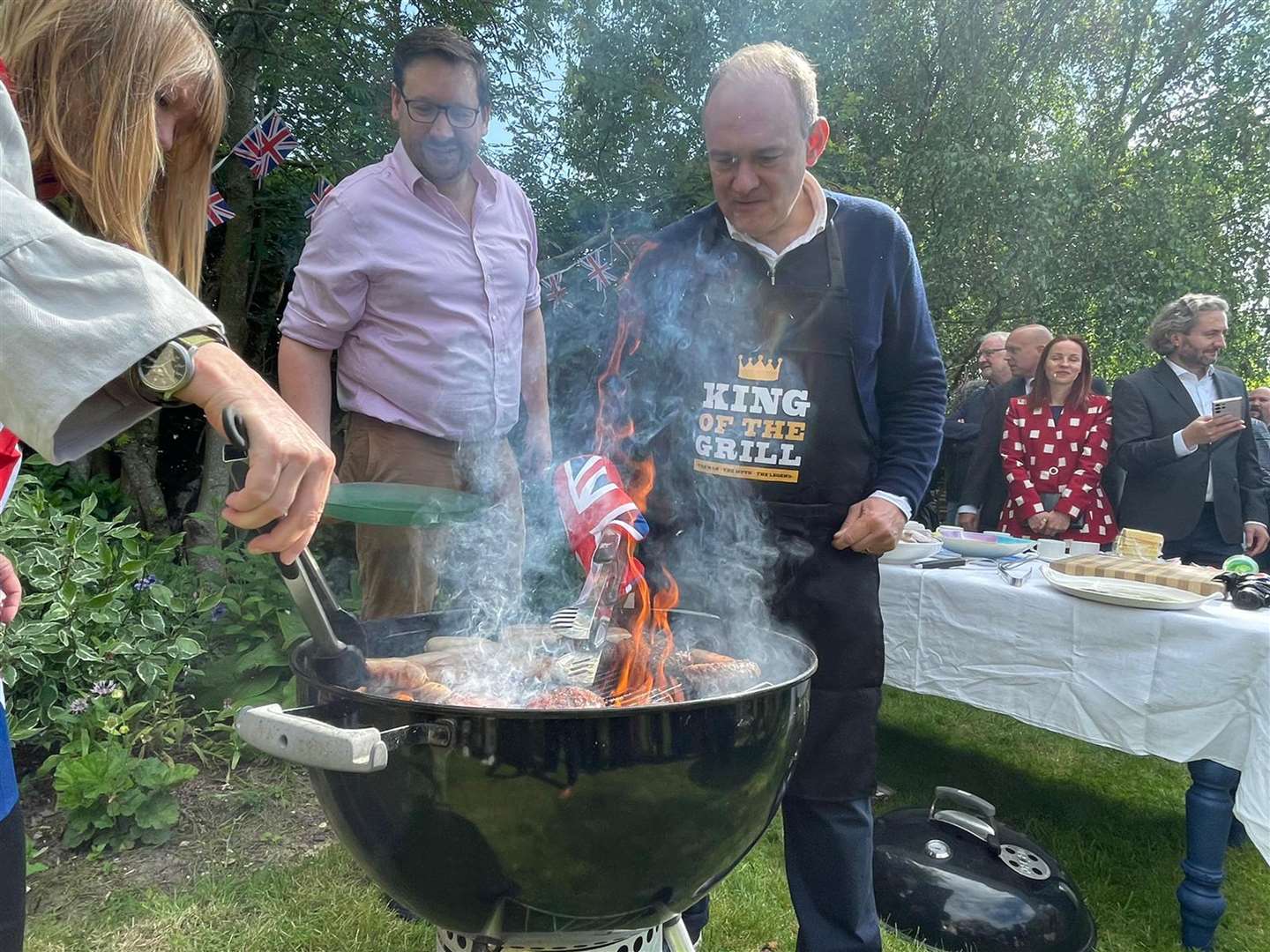 Sir Ed Davey, flipping burgers in a back garden barbecue (Will Durrant/PA)