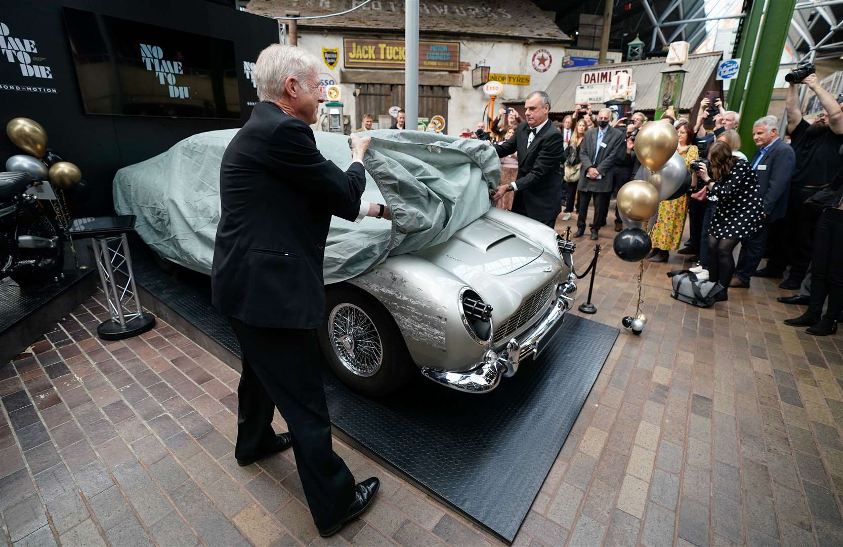 Lord Montagu of Beaulieu and Chris Corbould, special effects supervisor on No Time To Die, pull back the covers on a stunt replica Aston Martin DB5 (Andrew Matthews/PA)