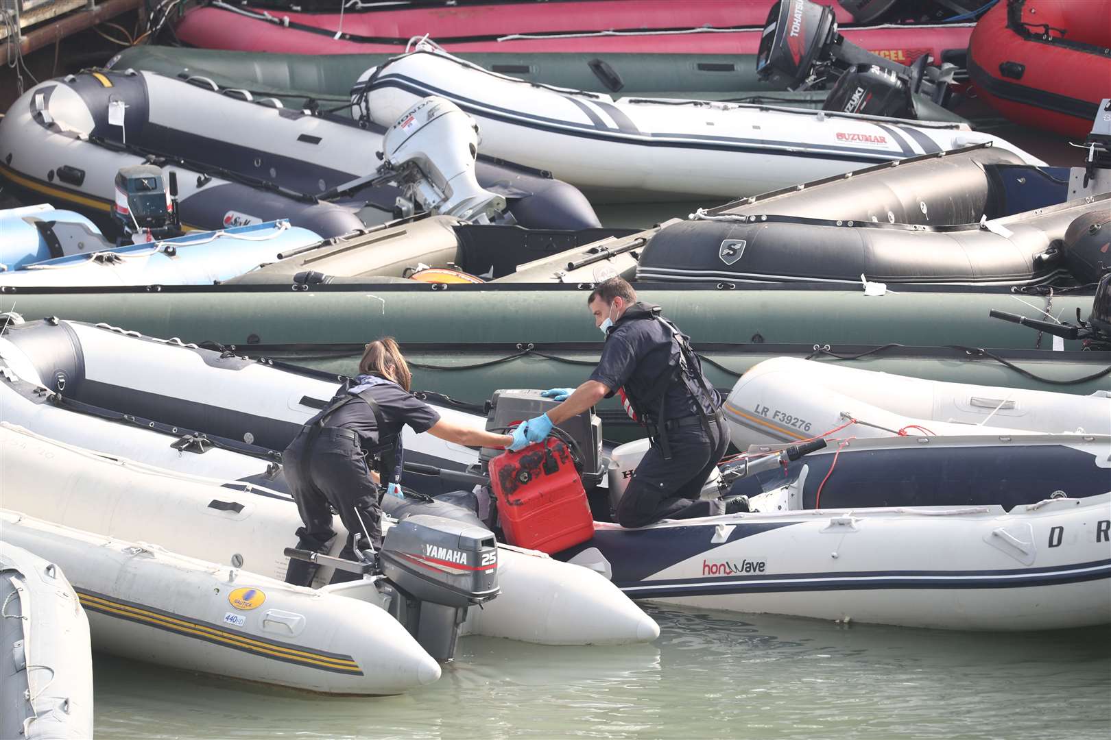 Two Border Force officers attending to a collection of ribs and dinghys, thought to have been used in small boat incidents in the English Channel (Gareth Fuller/PA)