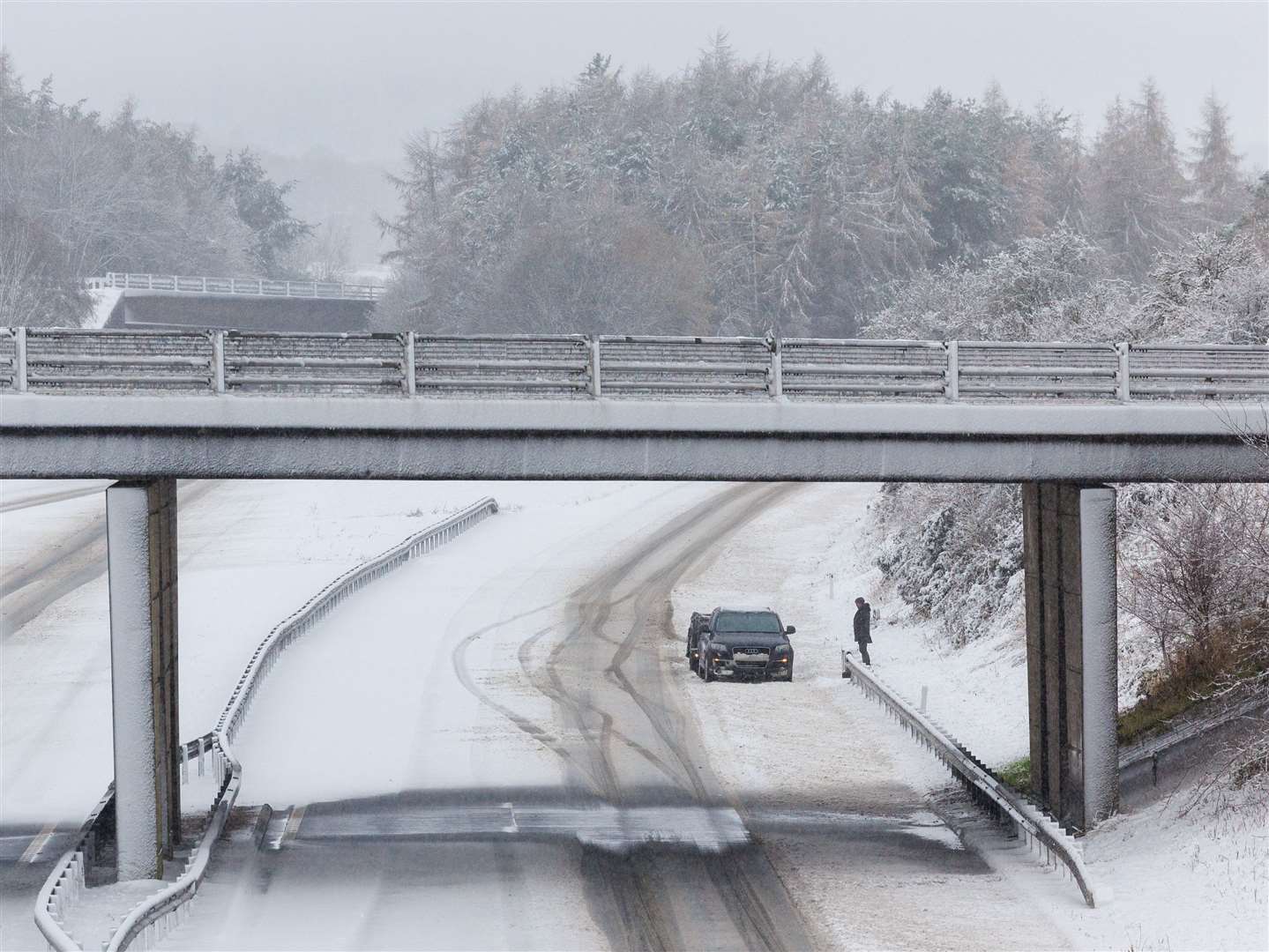 A person stands next to his vehicle on an empty snow-covered M9 motorway near Stirling (Robert Perry/PA)