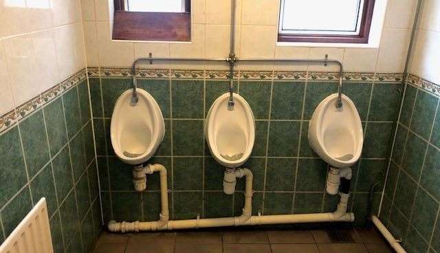 The gents’ toilet is traditionally tiled on both the floor and walls. There was a slanted board covering the base of the windowsill to the left.