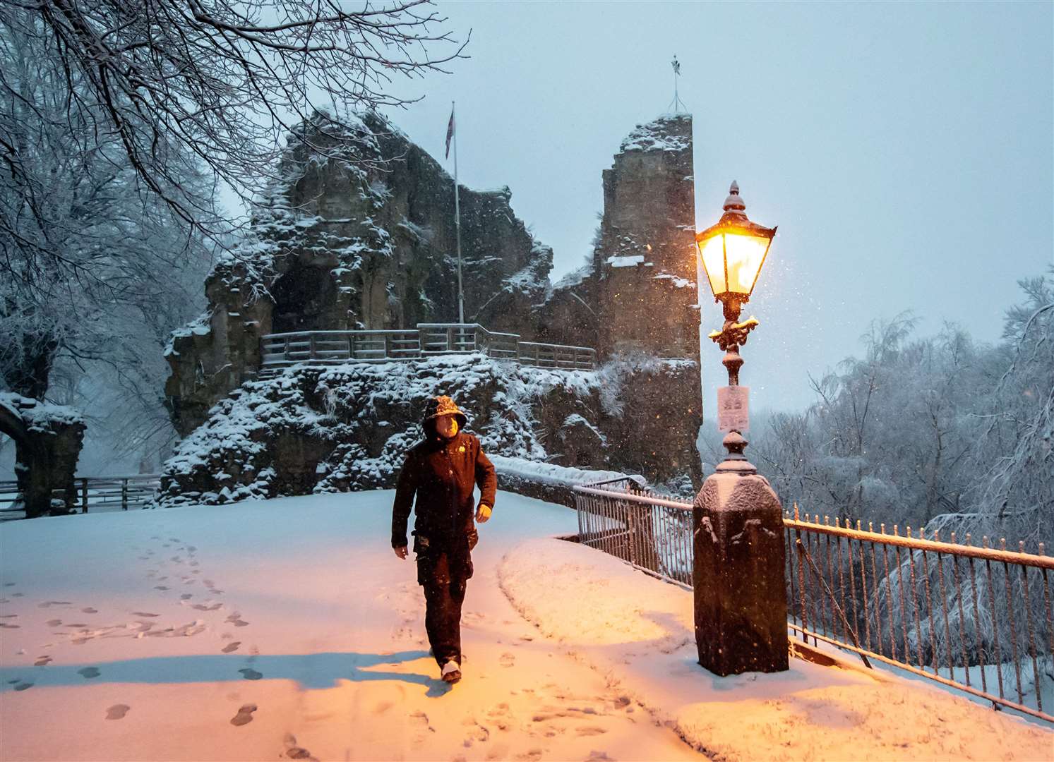 A light guides the way as a man walks near Knaresborough Castle in the snow (Danny Lawson/PA)