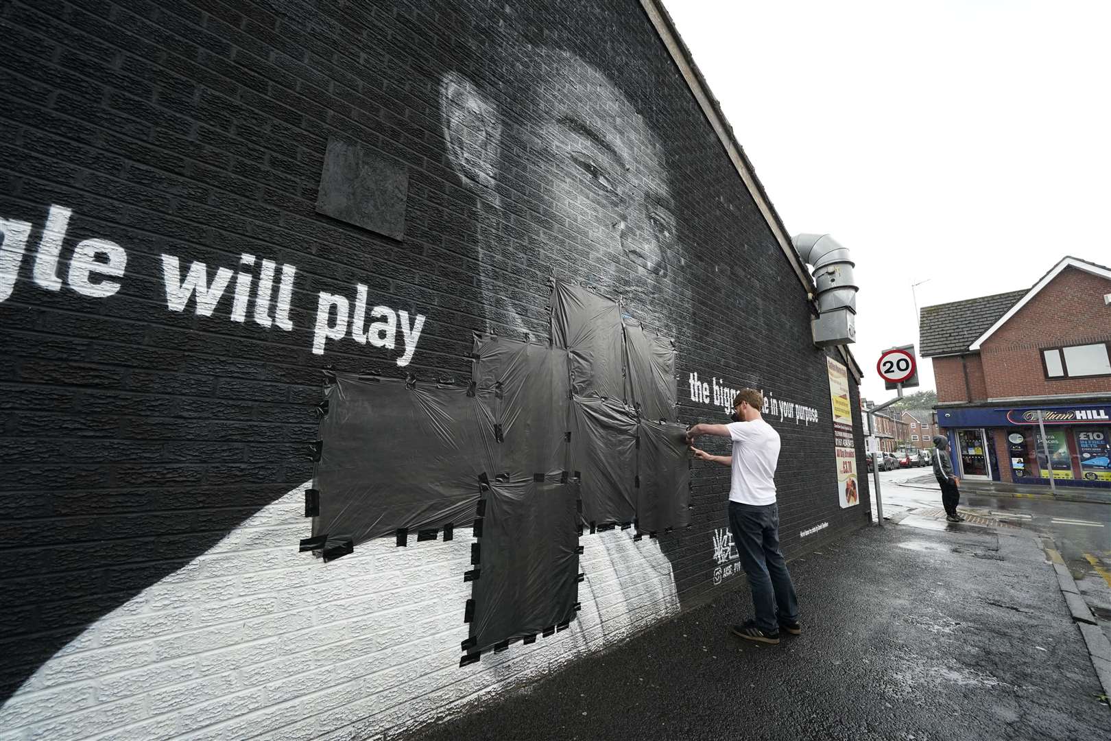 Ed Wellard tapes bin liners across offensive wording on the mural of Manchester United striker and England footballer Marcus Rashford (Peter Byrne/PA)