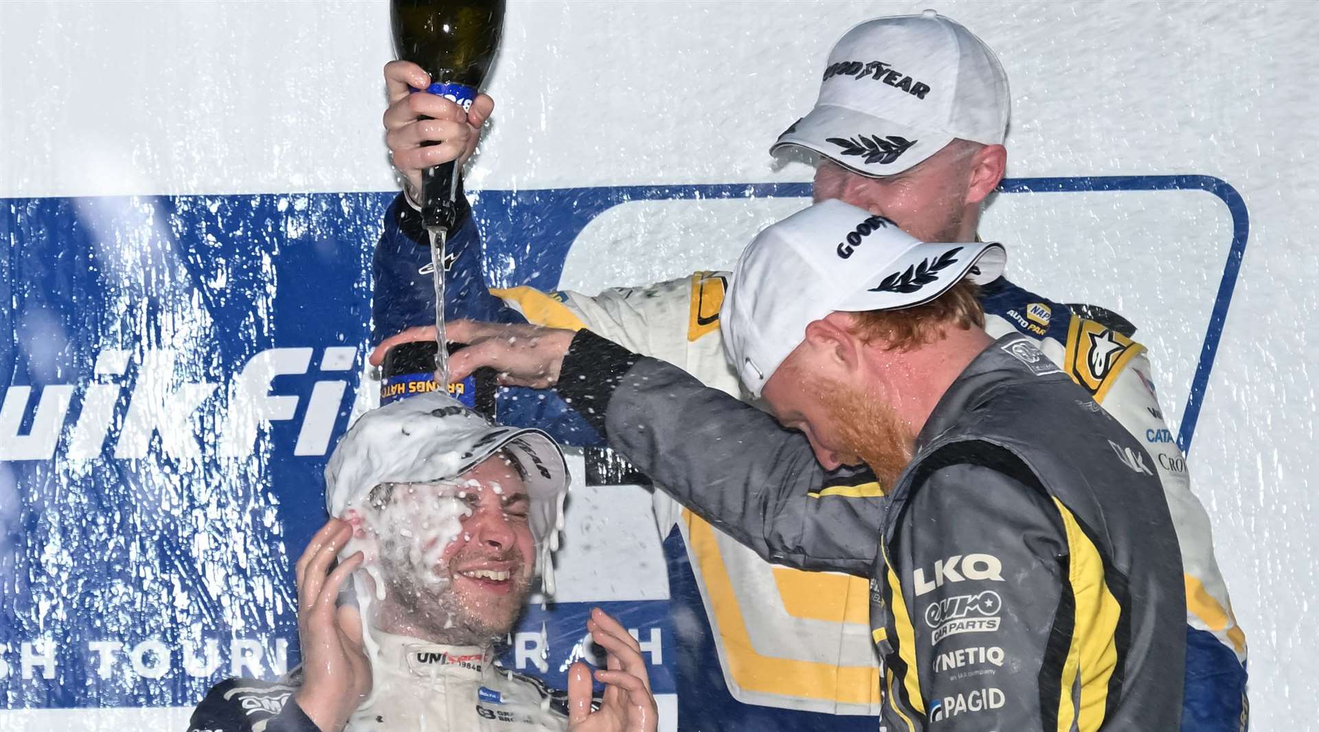 Race three winner Ash Sutton and third-place finisher Josh Cook soak Hill on the podium. Picture: Simon Hildrew